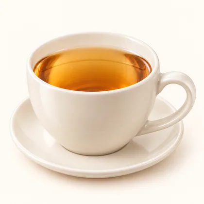 Aromática ámbar clara servida en taza crema sobre un plato pequeño.