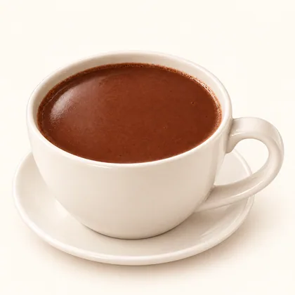 Chocolate en agua de superficie lisa servido en taza crema sobre un plato pequeño.