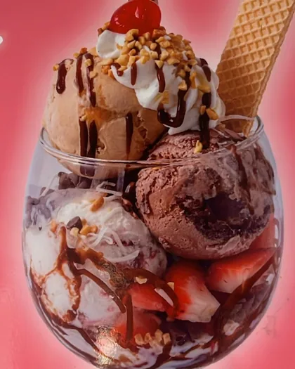 Copa de helado con frutas, crema, maní, cereza, barquillo y galleta sobre fondo rosado.