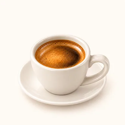 Espresso corto con crema avellana servido en taza pequeña color crema sobre un plato.
