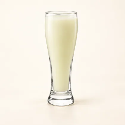 Jugo de guanábana color crema pálido servido en un vaso alto de vidrio transparente.