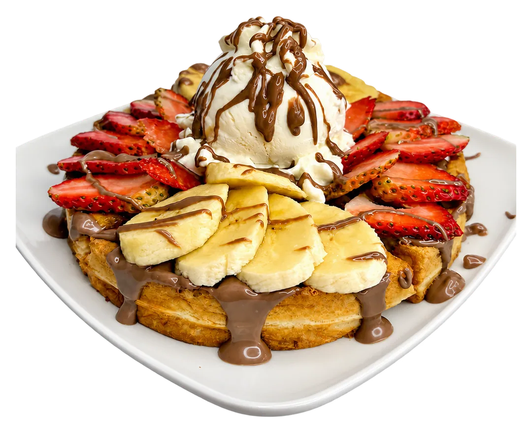 Waffle con banano, fresas, helado, crema y salsa de chocolate.