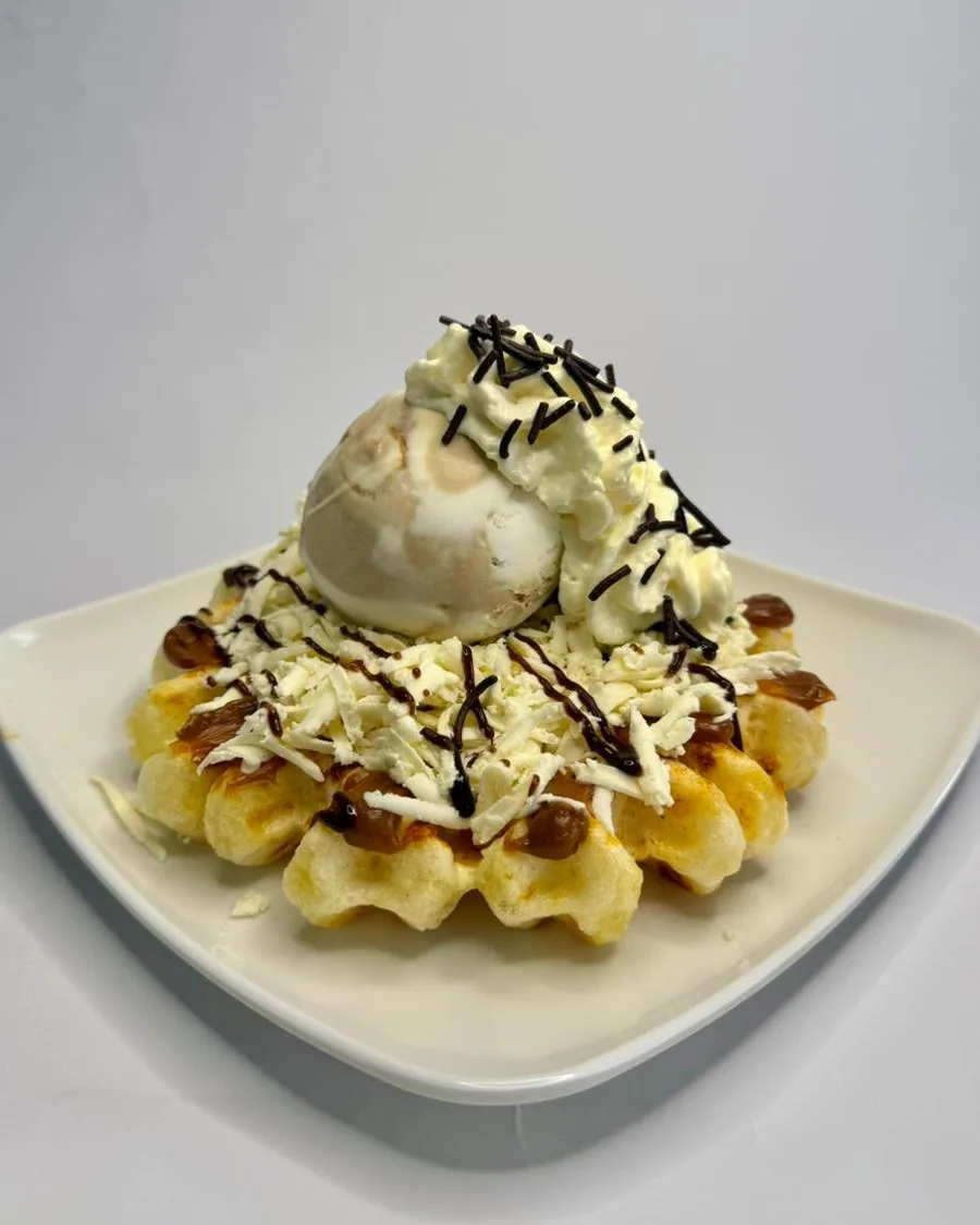 Waffle de pandebono con queso rallado, helado, crema, salsa de chocolate y arequipe.